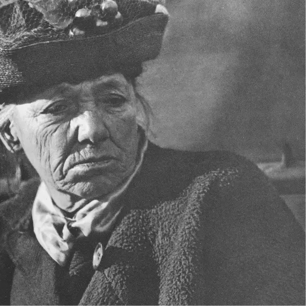 Elderly woman wearing a hat, in thought.